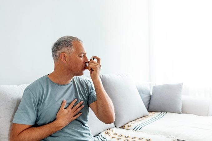 Mature man using asthma inhaler