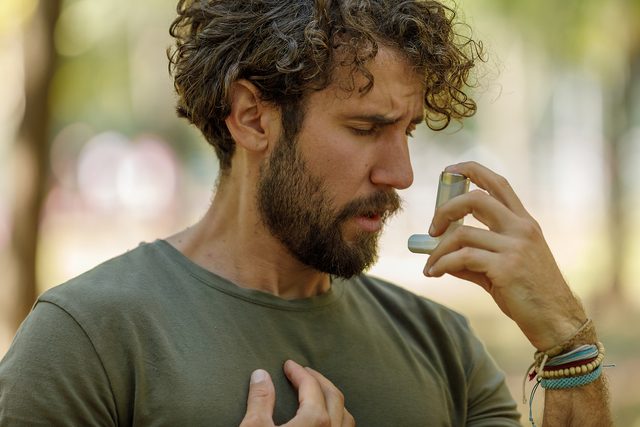 A Man is Using an Asthma Inhaler in Public Park.