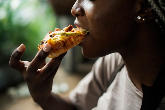 Young cheerful woman eating pizza