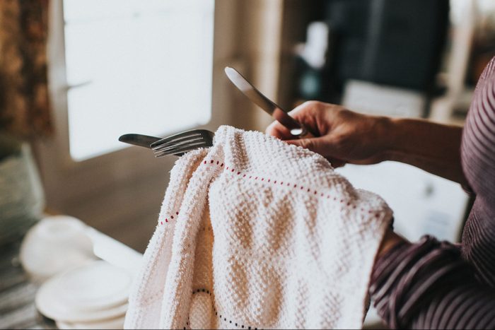 Woman drying Dishes with dish towel close up