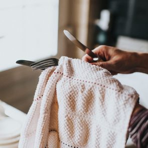 Woman drying Dishes with dish towel close up