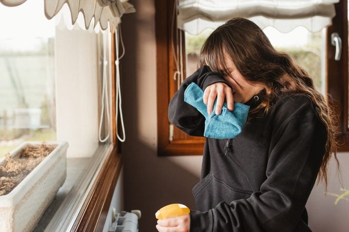 young woman cleaning a house and suffering from spring allergy headache