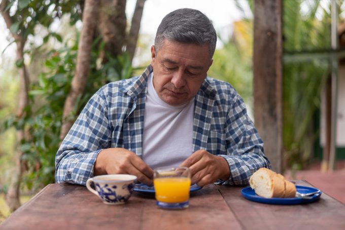 Adult man eating breakfast outdoors at his rural house