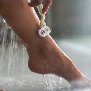 Close up of unrecognizable woman shaving her leg in shower water