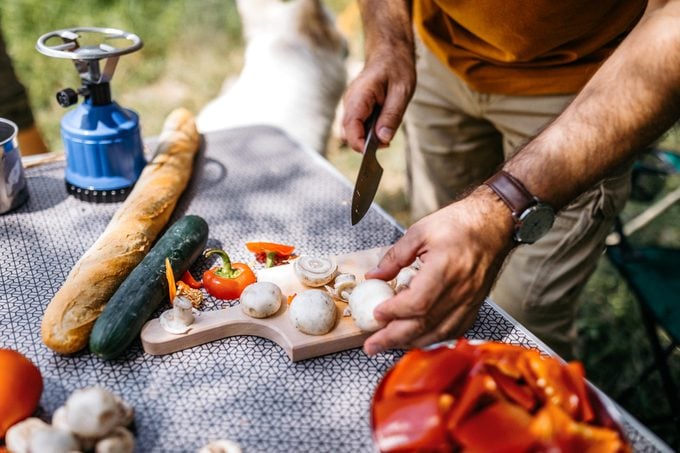 man cutting mushrooms and preparing vegetables to cook