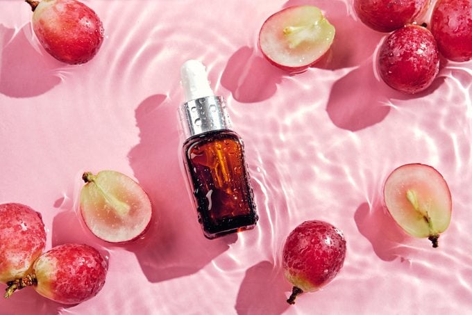grapeseed oil in cosmetic bottle on pink water background