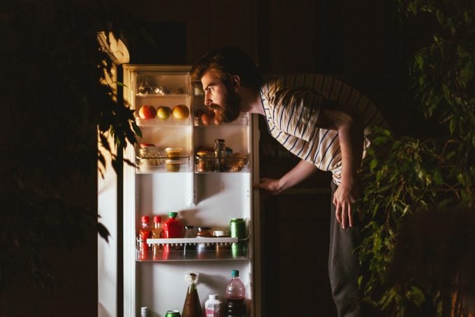 man looking in refrigerator late at night