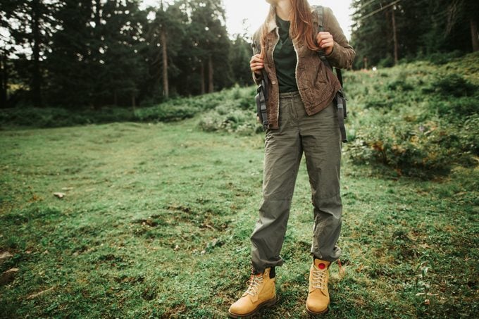 young woman wearing hiking pants standing on grass