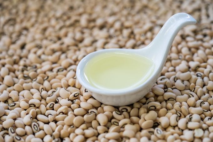 close up of soybean oil in ladle on top of soy beans
