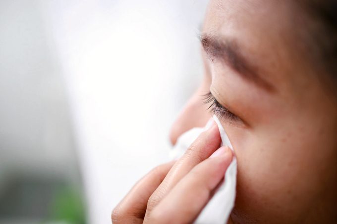 young woman wiping eye with tissue