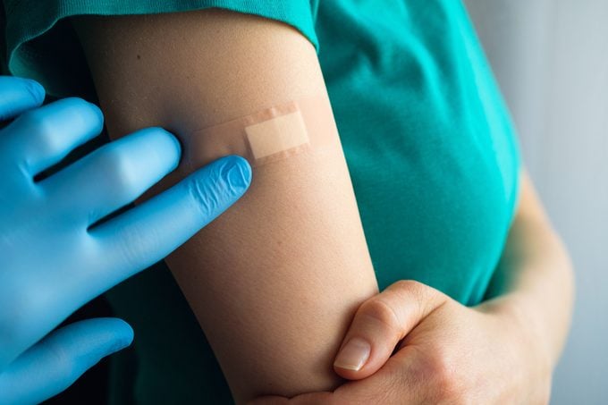 close up of doctor applying band aid to patient's arm after receiving a vaccine