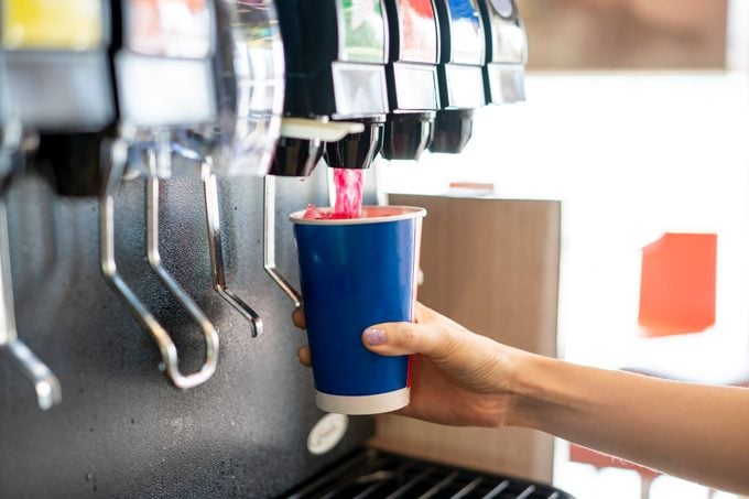 close up of person getting a soda from a fountain drink machine
