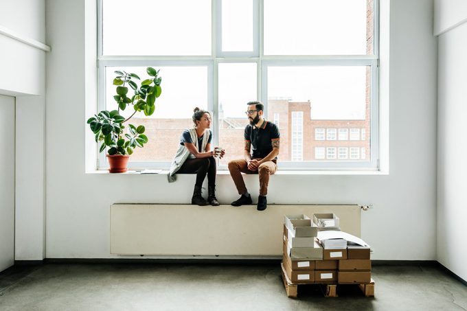 Jóvenes emprendedores sentados en una ventana hablando