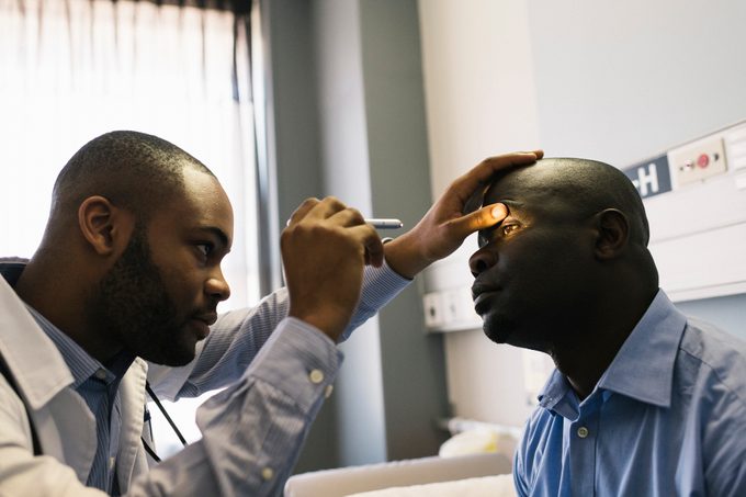 Young doctor uses ophthalmoscope to examine patient's eye