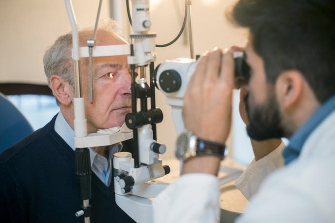 senior man having eyes examined by optometrist