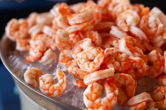 Large tray of cooked shrimp on ice