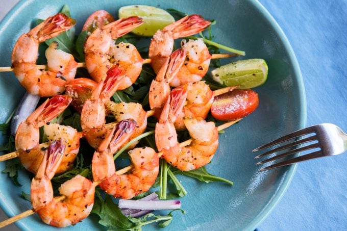 Grilled shrimp skewers with veggies on blue plate