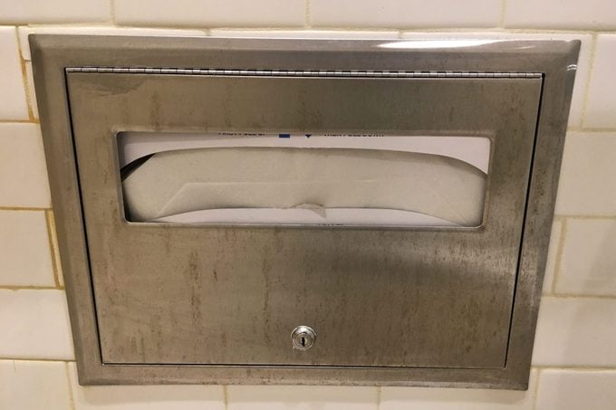 Toilet cover container mounted on a public bathroom stall wall