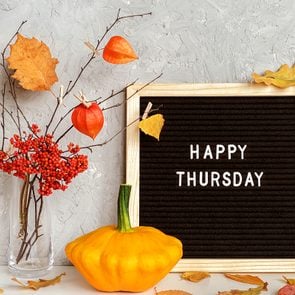 letter board sign that says happy thursday, surrounded by fall decorations