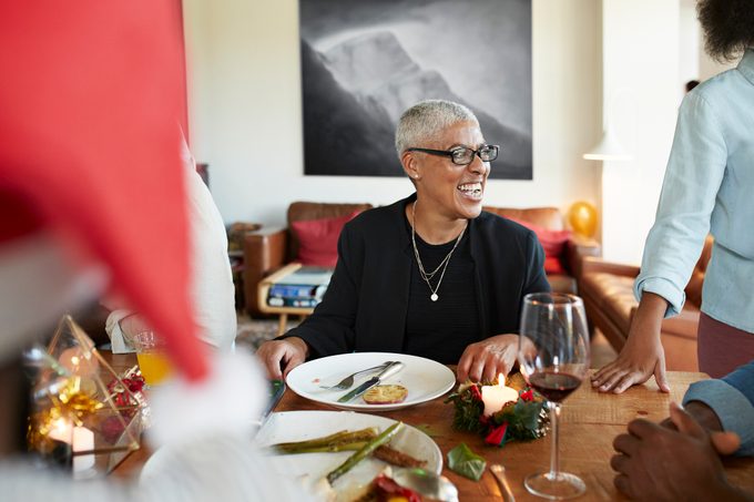 Mujer riendo mientras se sienta en la mesa para la cena de Navidad