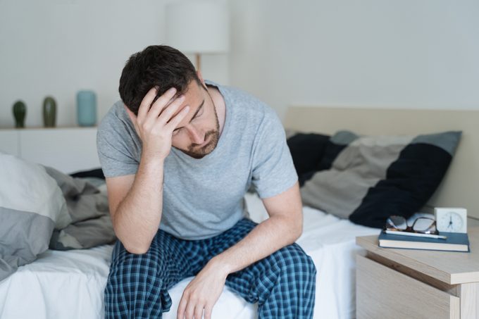 man waking up in bed with a headache not feeling well