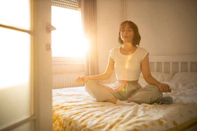 mulher praticando meditação em sua cama de manhã