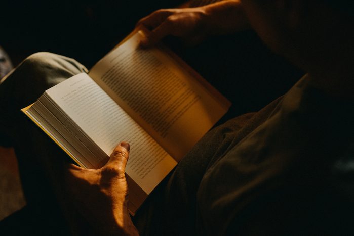 Man Reading a Book at home in the dark