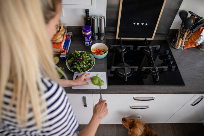 woman cutting an avocado while her dog watches her
