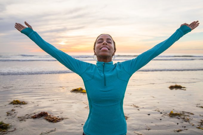 vrouw op het strand met handen in de lucht ter viering van het leven