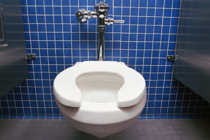 public toilet seat against blue tile wall