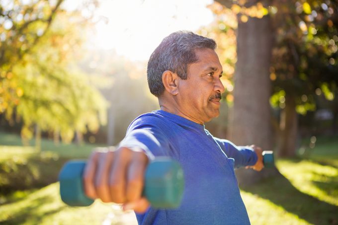 Man exercising with dumbbells on a sunny day outside
