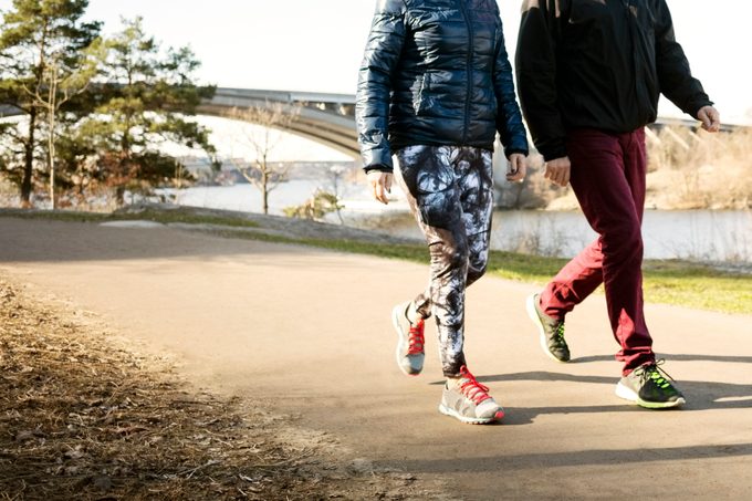 Low section of man and woman in sportswear walking on road outside during the fall