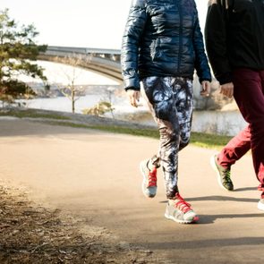 Low section of man and woman in sportswear walking on road outside during the fall