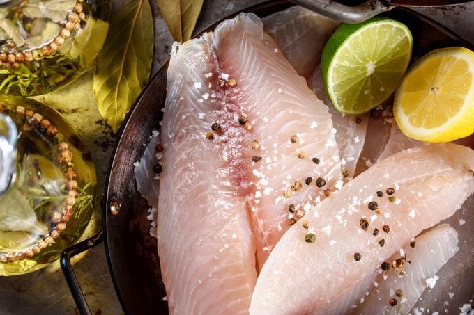 raw tilapia filet with citrus and spices