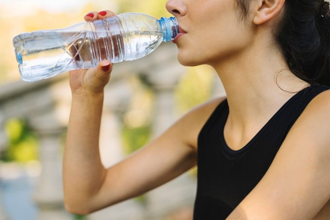 Close-up of young woman drinking from bottle after exercising
