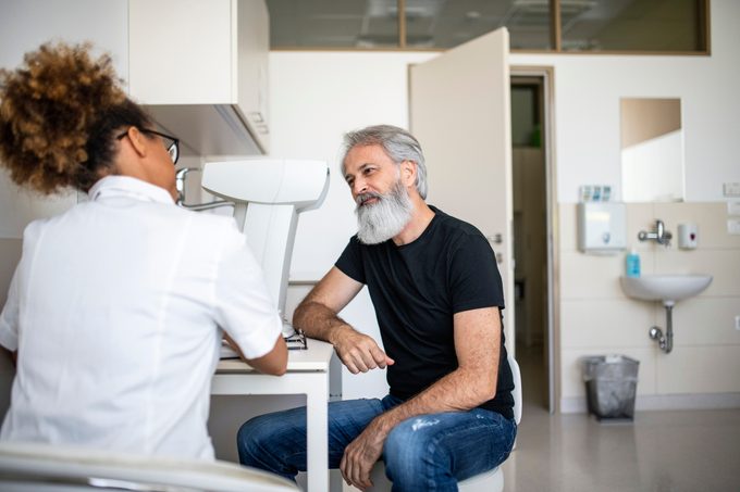 Mature man talking to an eye specialist in doctor's exam room