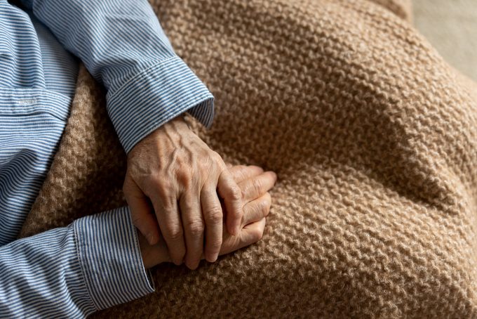 An elderly woman's hands on top of blanket while relaxing at home or in hospice care