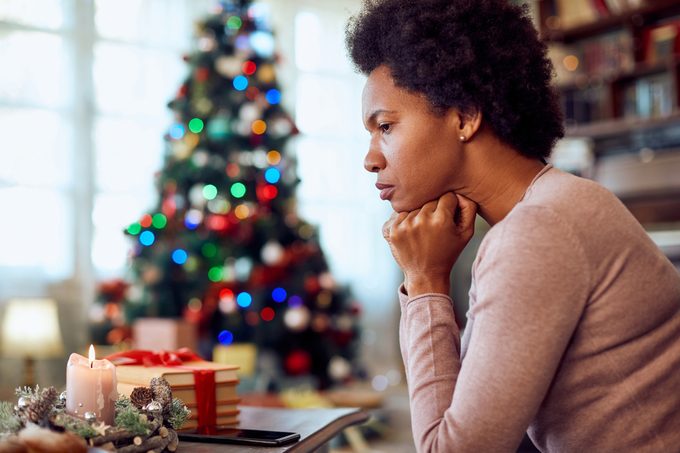 mujer preocupada sentada cerca del árbol de navidad