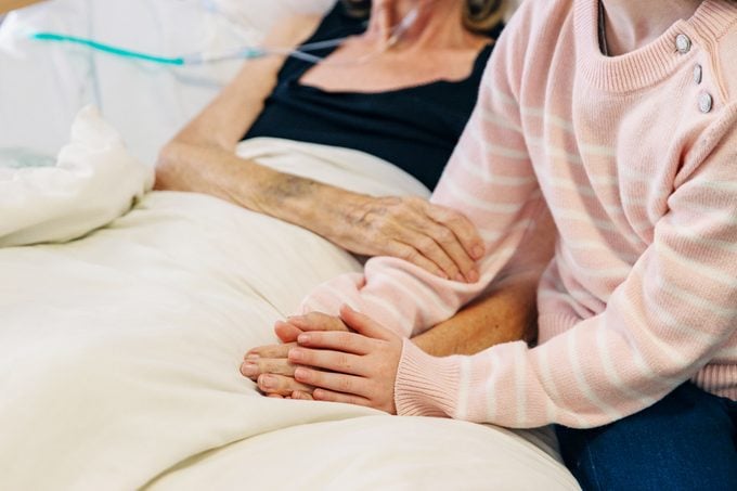 woman holding her mothers hands in hospice care