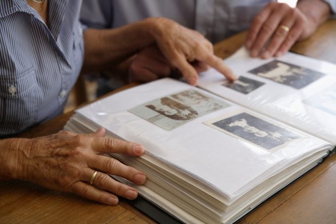 senior couple looking at old photo album together at home