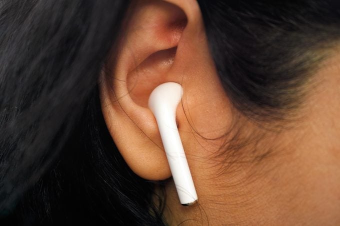 Close-up of wireless earbud in woman ear.