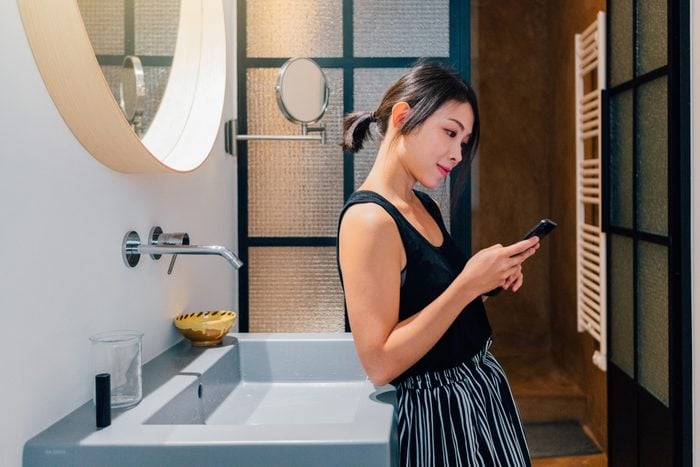 Young woman using mobile phone in the bathroom