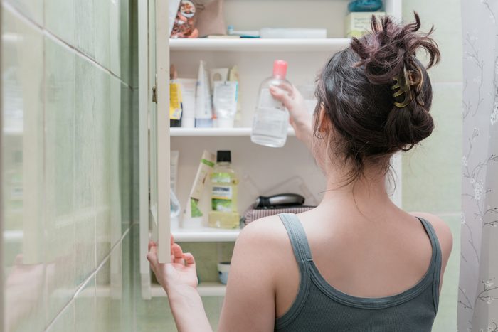woman taking something out of medicine cabinet in bathroom
