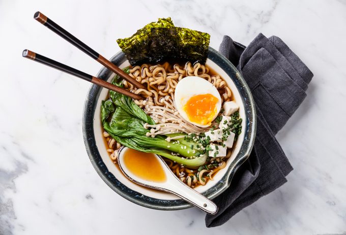 Miso Ramen Asian noodles with egg, enoki and pak choi cabbage in a bowl on white marble background