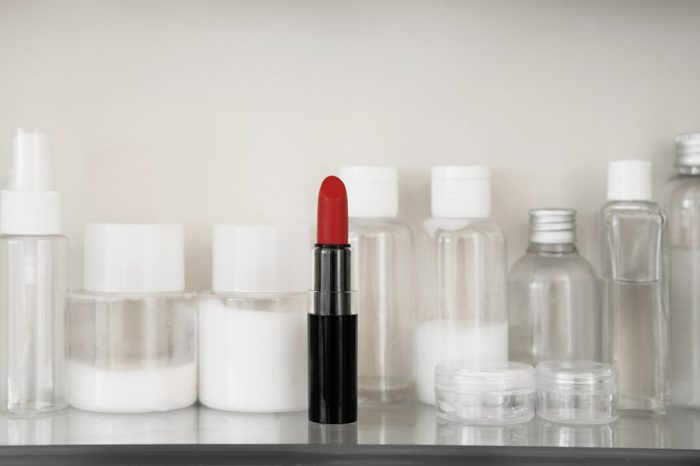 red lipstick among various other products on shelf in medicine cabinet
