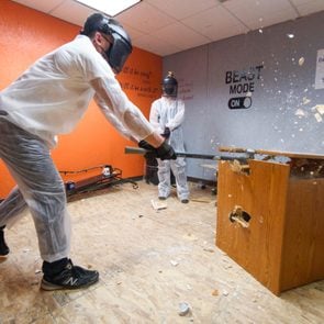 a person used a sledgehammer on a wooden piece of furniture during a therapy session in a rage room
