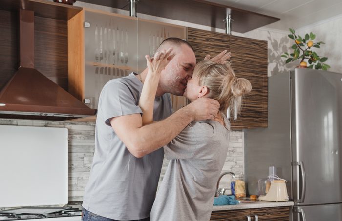 happy young couple kissing in the kitchen smeared with flour