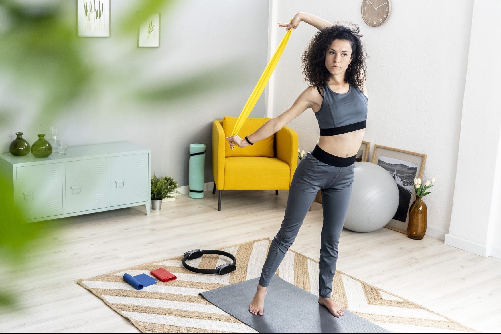 Young woman looking away while exercising with resistance band at home