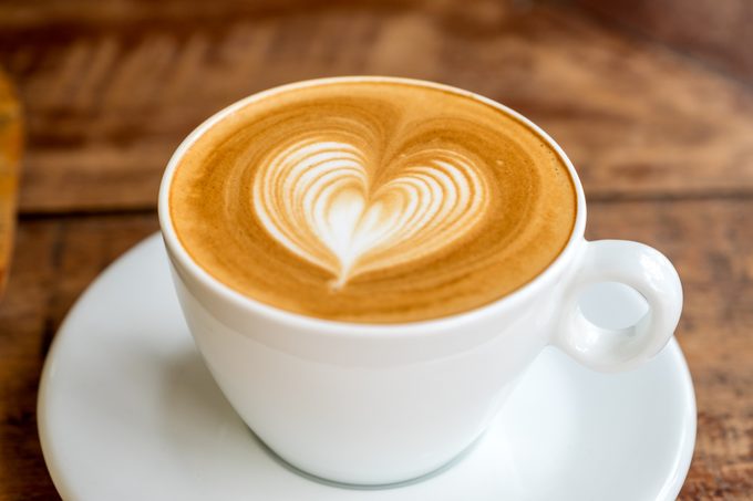 Taza de café con leche con arte latte en forma de corazón de cerca
