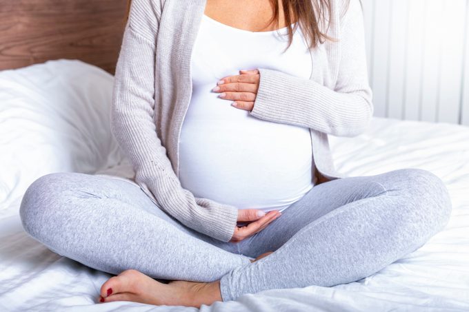 Uma mulher grávida segurando a barriga do bebê em casa